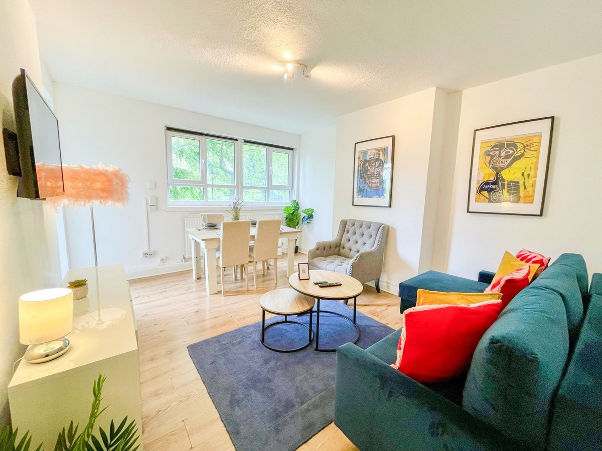 Living and dining room with a teal sofa and red cushion