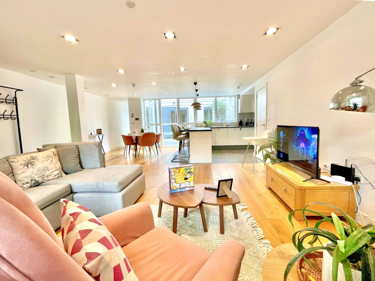 Open-plan living room with sofas, television and a kitchen beyond